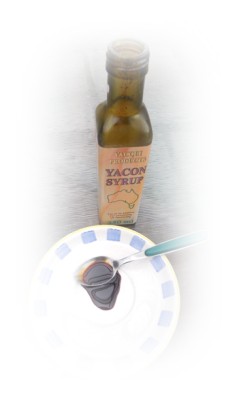 A bottle of Yacon Syrup with a teaspoon of the thick dark syrup on a plate